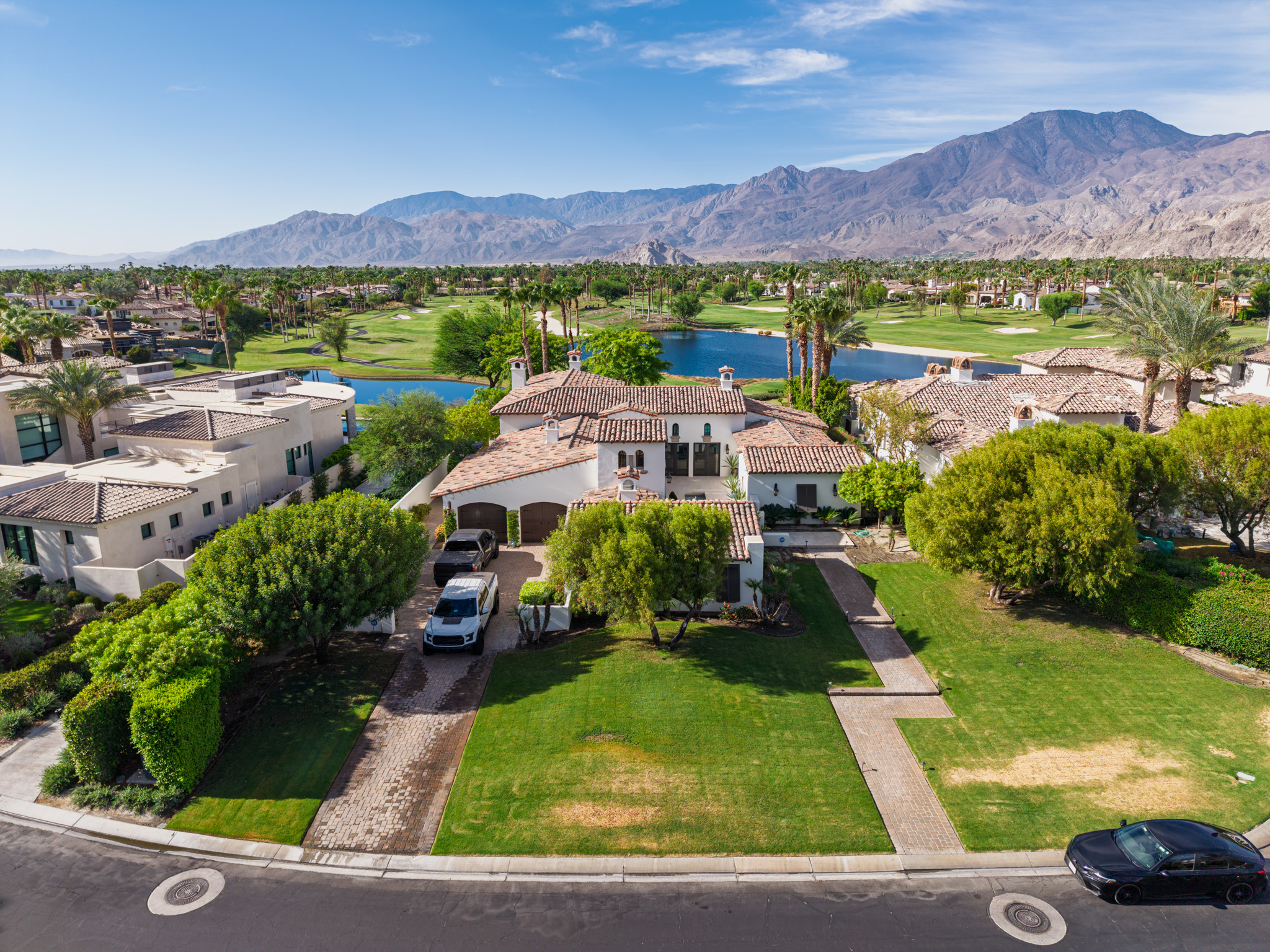Aerial view of a desert estate with its golf-course setting and surrounding mountains